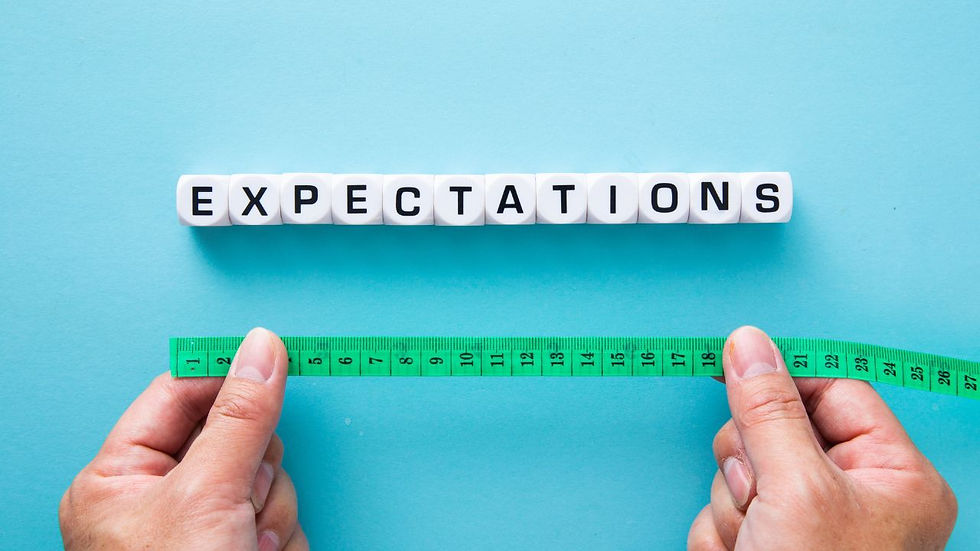 Hands hold a green measuring tape below cubes spelling "EXPECTATIONS" on a blue background, symbolizing measurement of expectations.