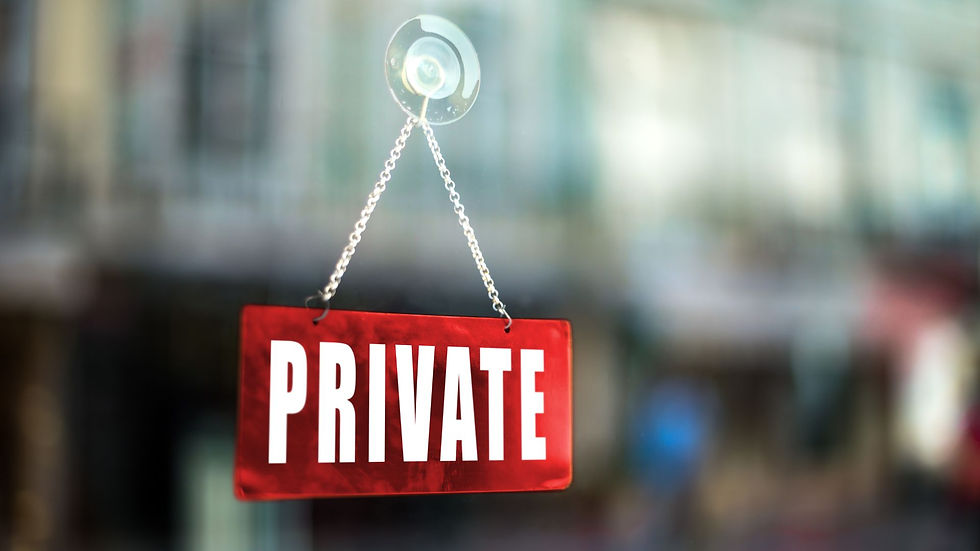 Red "PRIVATE" sign hanging on a chain, attached to glass with a suction cup. Blurred background suggests an indoor setting.
