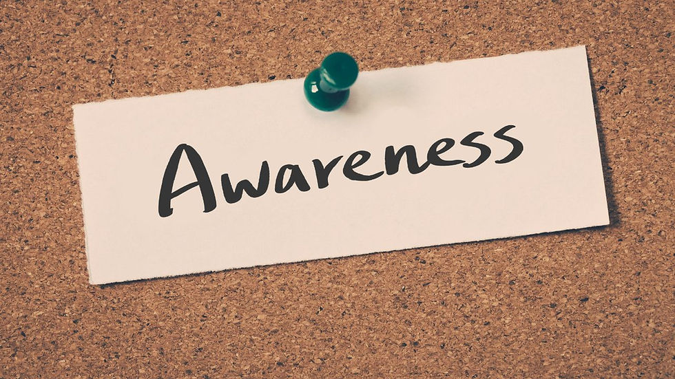 A corkboard displays a white card pinned with a green pushpin. The card reads "Awareness" in bold black script.