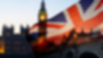 A Union Jack flag waves in the foreground, while the iconic silhouette of Big Ben and the Houses of Parliament are visible in the blurred background at dusk.