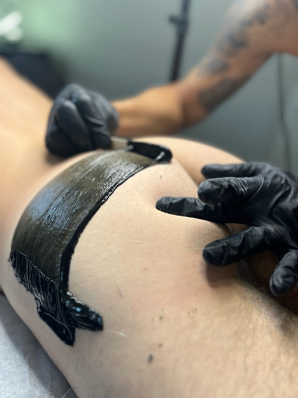 (Waxing treatment on glutes): “BootyBossLA technician applying a wax treatment to a client’s glutes for smooth and hair-free