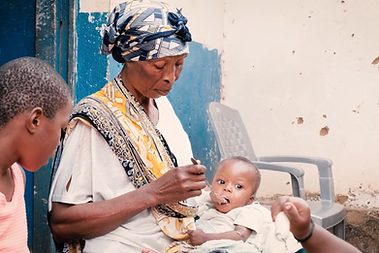 Grandmother feeding her grandchild at the malnutrition program