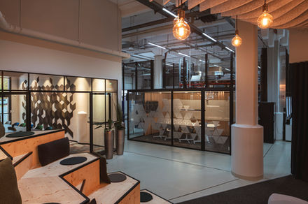 Offene Arbeitswelt in einem modernen Büro mit Sitztreppe, Glas-Meetingräumen und industriellem Design