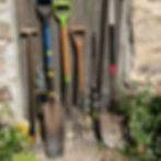 Assorted gardening tools leaning against an old wooden garden shed door.