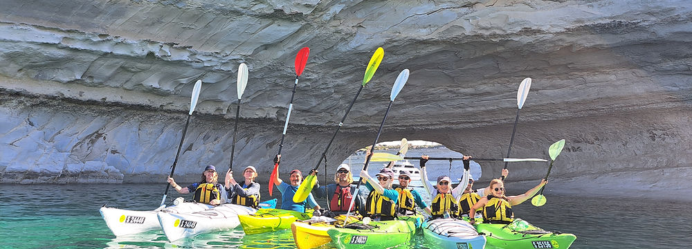 Happy group of sea kayakers in crystal clear waters beneath limestone cliffs near Il Ħofra, Malta
