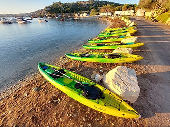 Rainbow Orca sit on top sea kayaks lined up at Mistra Bay Malta before a guided coastal kayaking tour.
