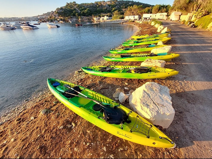 Rainbow Orca sit on top sea kayaks lined up at Mistra Bay Malta before a guided coastal kayaking tour.