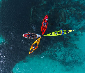 Four colourful sea kayaks forming a star pattern in clear Mediterranean waters viewed from above in Malta.