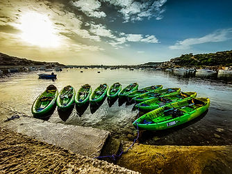 Rainbow Orca sea kayak fleet at Mistra Bay Malta ready for a guided kayaking adventure along the Maltese coastline.