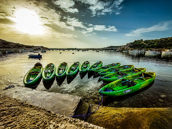 Rainbow Orca sea kayak fleet at Mistra Bay Malta ready for a guided kayaking adventure along the Maltese coastline.