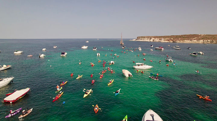 Drone view of a large kayaking gathering in San Tumas Bay, Malta, supporting marine ecotourism and environmental awareness.