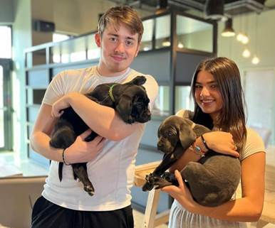 Two students pose with puppies at one of true student's animal therapy events at their student accommodation sites