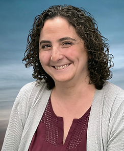 Headshot of Cynthia Heryanto, speech-language pathologist and owner of Communication Horizons. She is smiling, with shoulder-length curly brown hair, wearing a maroon shirt and gray cardigan