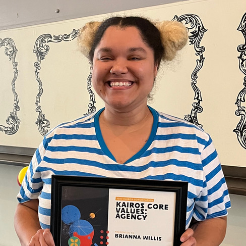 A woman smiles as she holds a Kairos Core Value Award