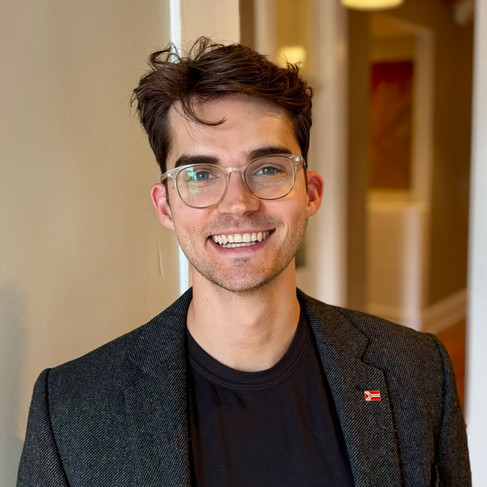 A man in a jacket smiles for a portrait.