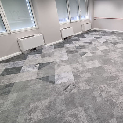 Modern office featuring a stylish arrangement of light and dark grey carpet tiles, creating a sleek and contemporary floor design.