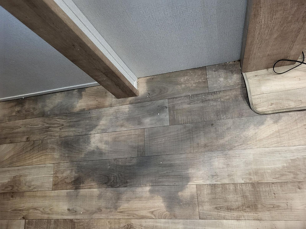 Discoloured sheet vinyl flooring showing extensive water damage after a leak, with visible dark stains and uneven surface.