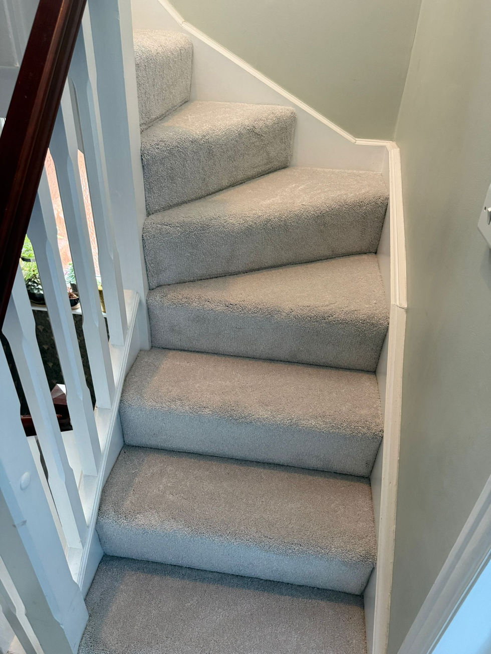 Carpeted staircase with white railing and walls.