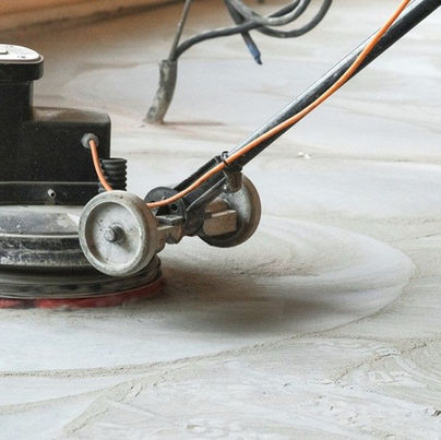 A floor sanding machine is being used to remove layers of old adhesive