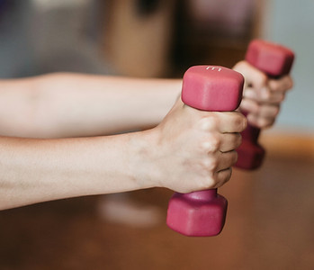 Woman holding dumbbells to represent restorative exercise training for strength and wellness.