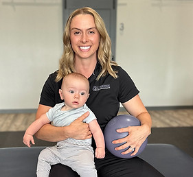 Miki Eaton smiling while holding a baby in her Sheboygan office, representing h