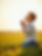 Boy kneeling in field, praying at sunset