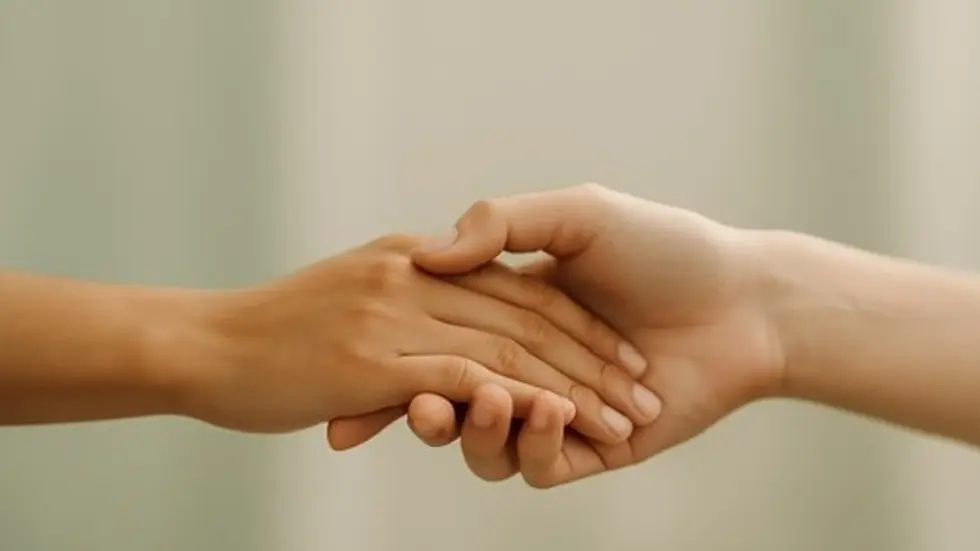 Two hands gently holding each other, symbolizing connection and self-worth through therapy.