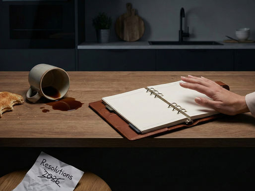 A leather planner next to spilled coffee, symbolizing the stress of working motherhood and failed New Year resolutions.