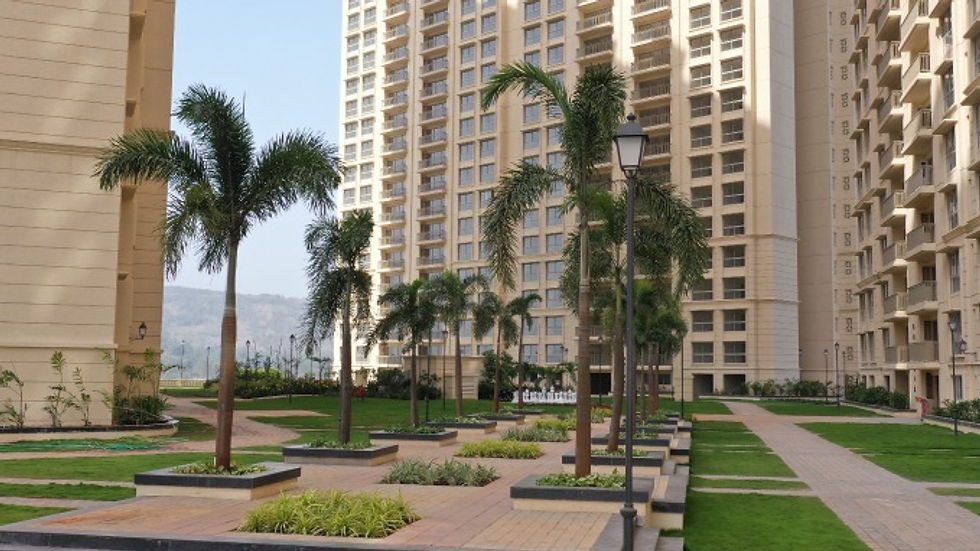 Street-level view of a family walking along landscaped pathways near residential towers in Panvel