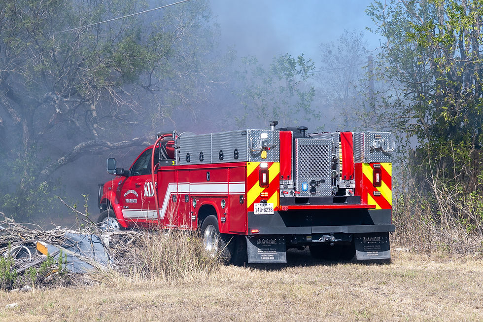 A firetruck is parked in a burnt field. 