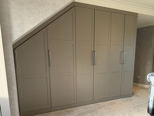 Custom fitted wardrobes with multi-panel Shaker doors, precision-built to fit perfectly under a sloped ceiling.