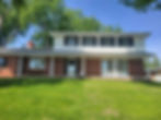Front facade of two-story brick and white vinyl siding colonial home in Iowa with black shutters and