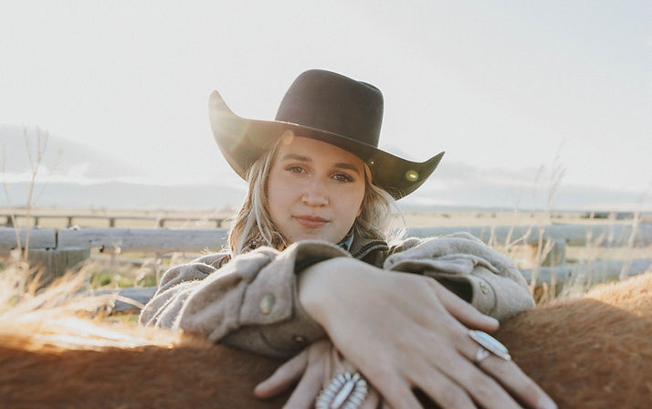 Girl standing beside a horse with her hands over its back