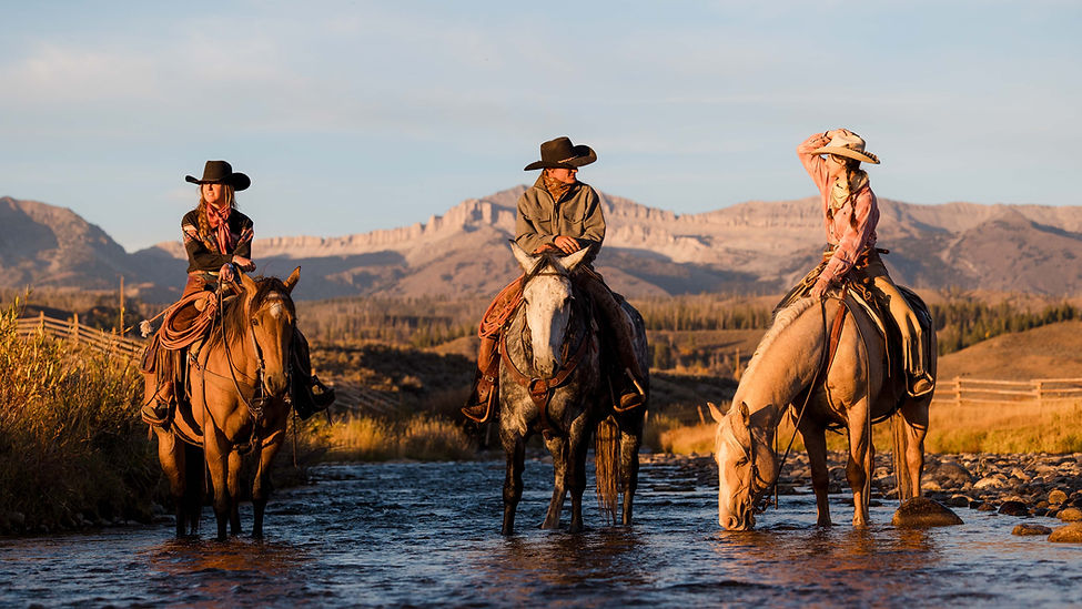 Group of three riders on horses standing in flowing river water