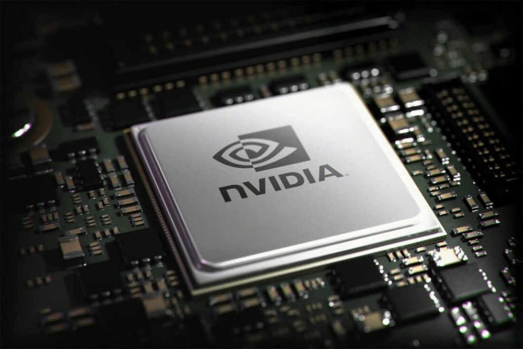 Imagem mostra um chip de computador prateado, com o logo e o nome "NVIDIA" em preto, centralizado em uma placa-mãe escura cheia de pequenos componentes eletrônicos. 