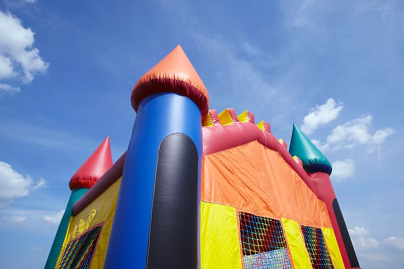 Colorful inflatable bounce house with blue, red, and orange sections under a clear blue sky, creating a playful, cheerful mood.