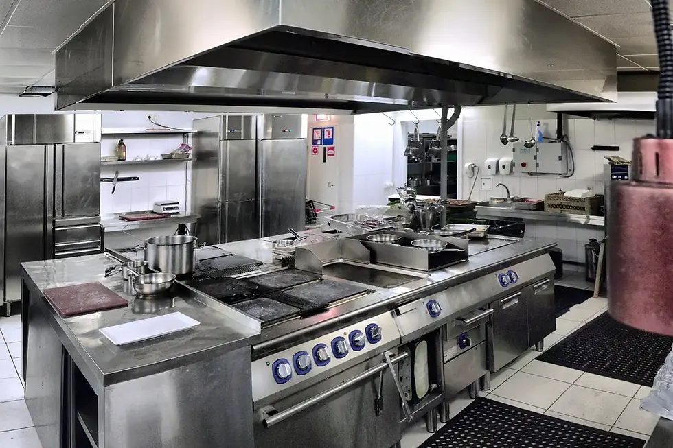 Mobiliario para cocina industrial con superficies metálicas, campana extractora y refrigeradores profesionales