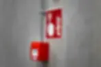 Sistema fijo contra incendio con pulsador manual de alarma sobre pared de concreto en zona de emergencia.