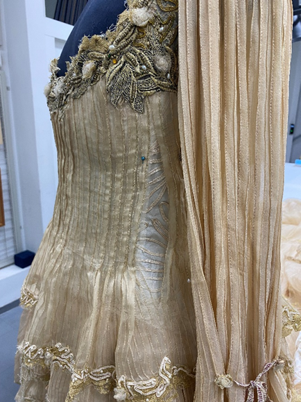 Detalhe de vestido em manequim passando por processo de conservação e restauro