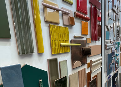 A wall displaying lots of tiles in different colours, shapes, sizes, and patterns, organised by colour