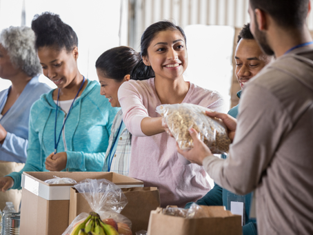 Volunteers working in a food bank passing items to another volunteer