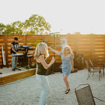 Happy customers enjoying drinks, live music, and games in the Flint Station Beer Garden