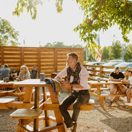 Happy customers enjoying drinks, live music, and games in the Flint Station Beer Garden