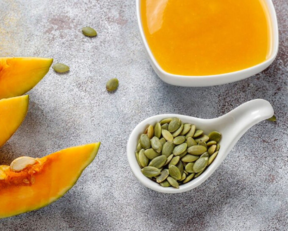 Κολοκυθόσπορος μέσα σε κουτάλι μαζί με φέτες κολοκύθας και κολοκυθόσουπα σε μπολ.