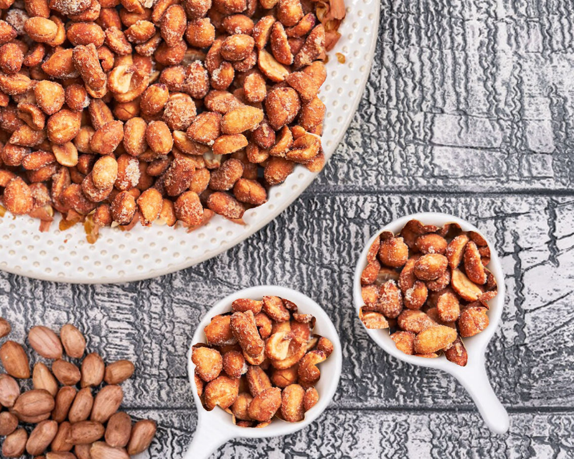 Αράπικα φυστίκια αλατισμένα μέσα σε λευκά μπολ επάνω σε ξύλινο γκρι τραπέζι