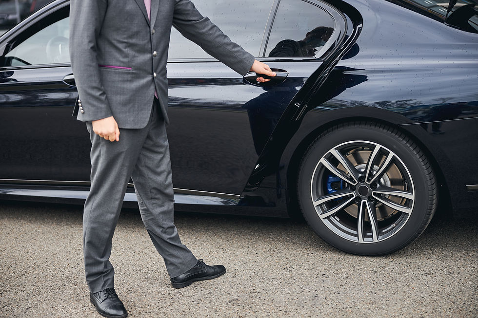 Cropped photo of a driver in a stylish suit opening the car door for his passenger.jpg