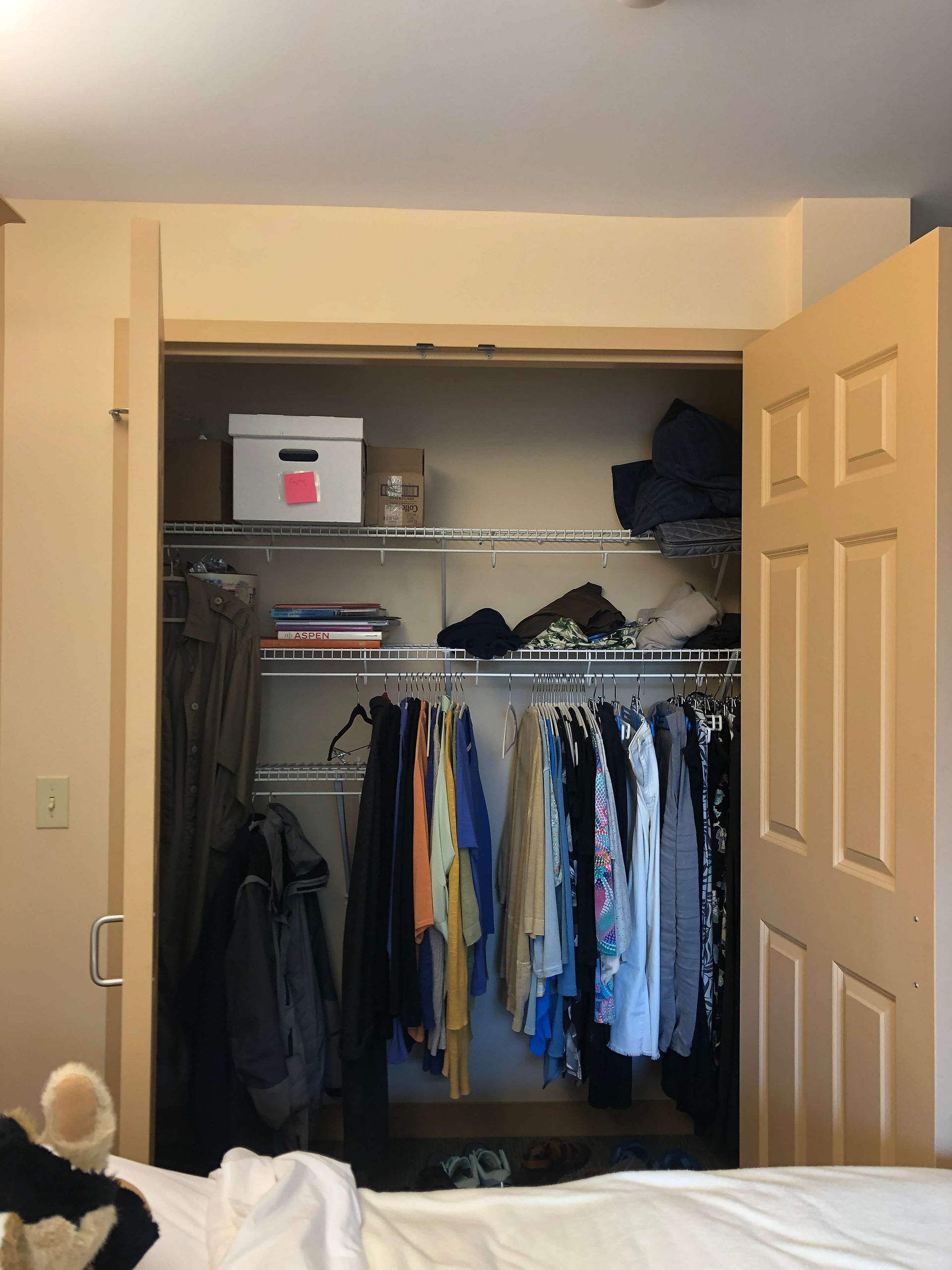 disorganized clothes closet with swing doors