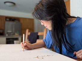 Jennifer painting gold letters on a white canvas