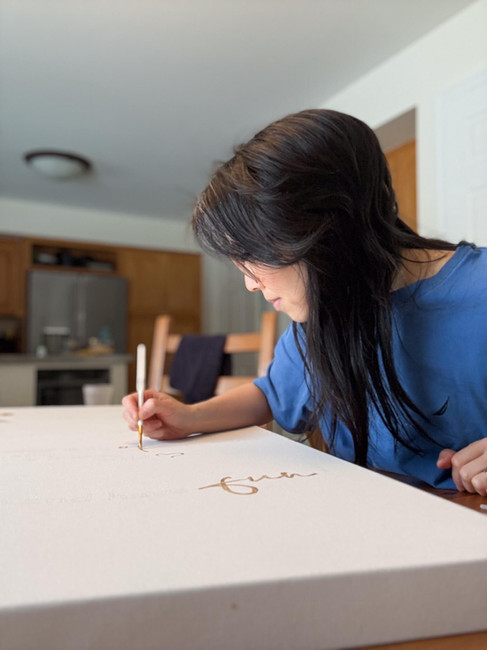 Jennifer painting words gold on canvas