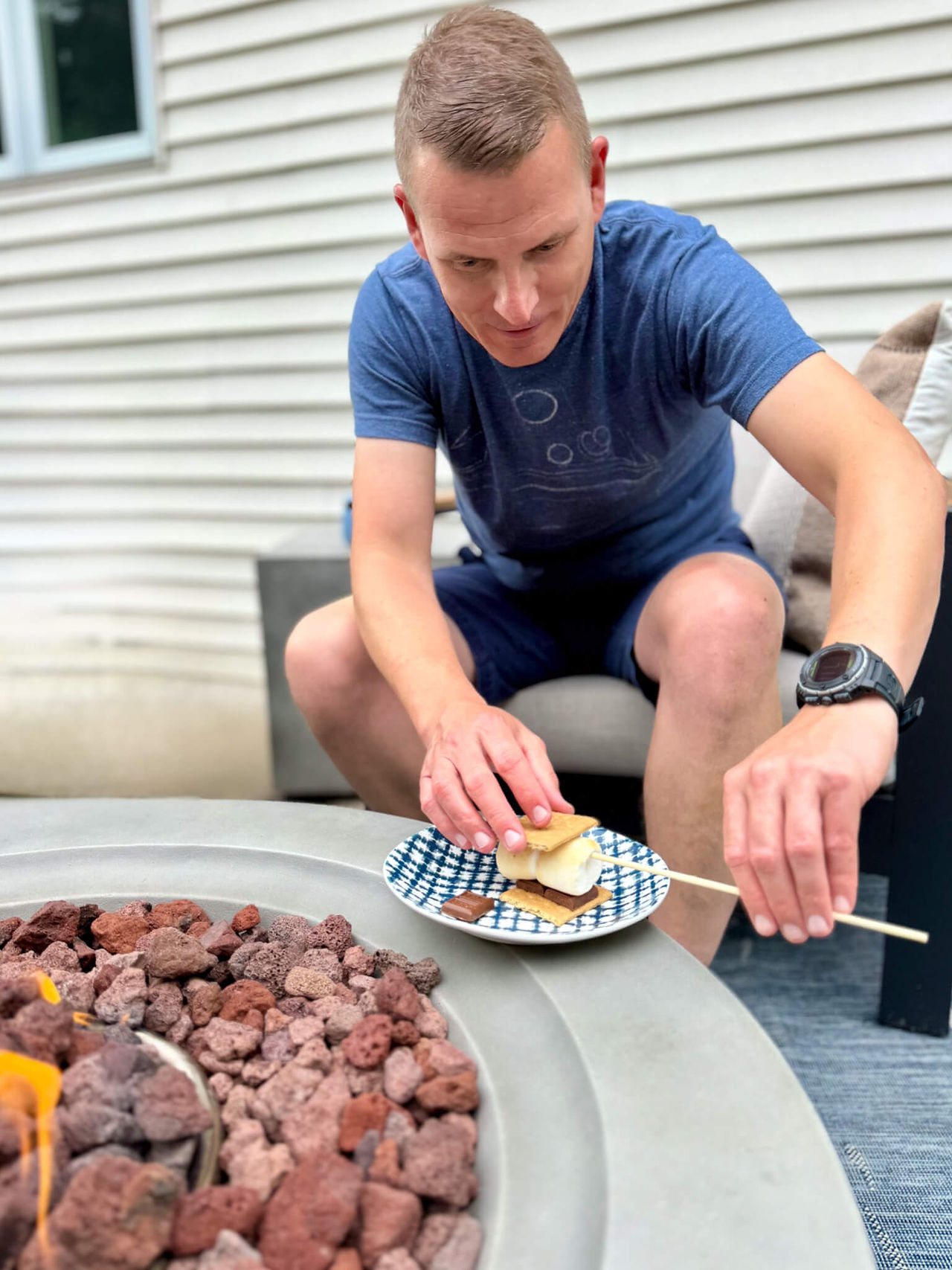 man putting roasted marshmallow between graham cracker and chocolate